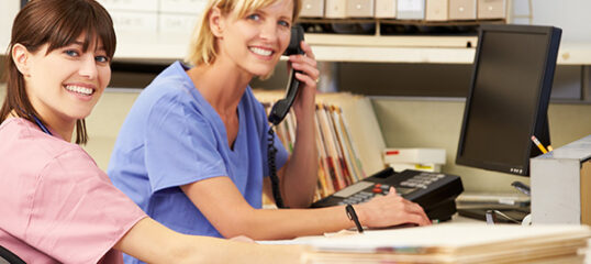 Two Nurses Working At Nurses Station